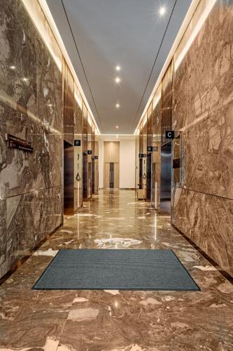 a lobby with a marble wall and a hallway with a rug at A La Carte Ha Long Bay Managed by TASECO in Ha Long