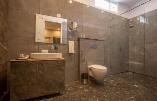 a bathroom with a toilet and a sink and a mirror at Hotel The Prithvi Near Delhi Airport in New Delhi