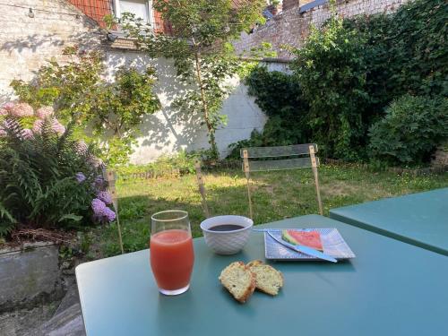 ein blauer Tisch mit einem Glas Orangensaft und Keksen in der Unterkunft La charmante petite maison in Croix