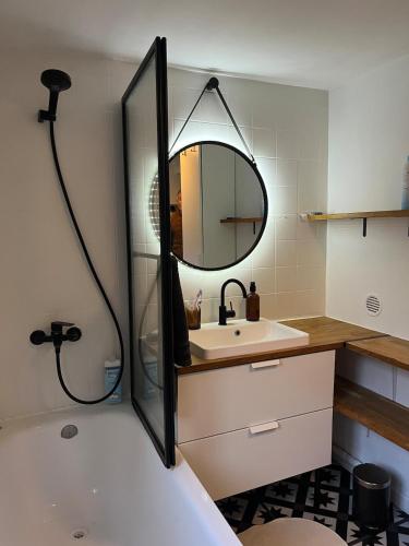 a bathroom with a tub and a sink and a mirror at La charmante petite maison in Croix