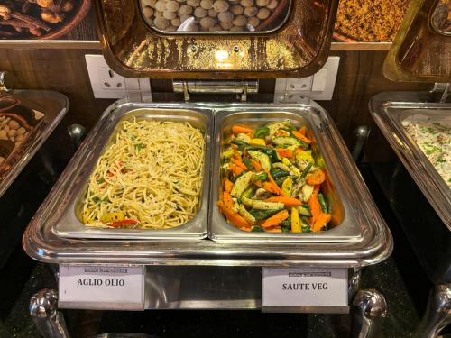 a tray of food with noodles and vegetables on display at Hotel Cardinal Express Oxmo Delhi Airport in New Delhi