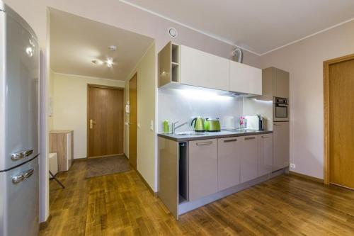 a kitchen with white cabinets and a wooden floor at Easty Stay Apartments - City Centre in Tallinn