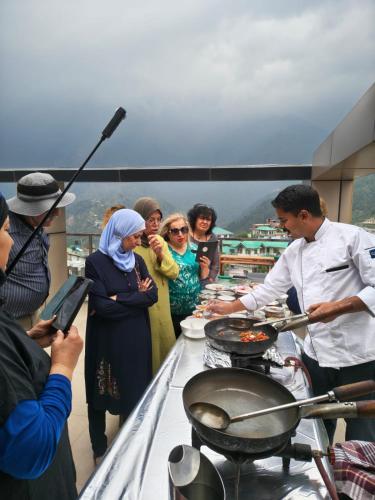 a group of people standing around a table with food at Aliza Inn And Suites By SRS Hotels in Dharamshala