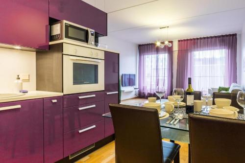 a kitchen with purple cabinets and a table with chairs at Easty Stay Apartments - City Centre in Tallinn