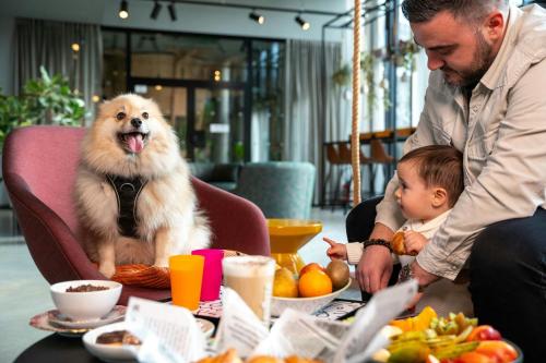 a dog sitting in a chair at a table with a child at Moxy Paris Val d'Europe in Montévrain