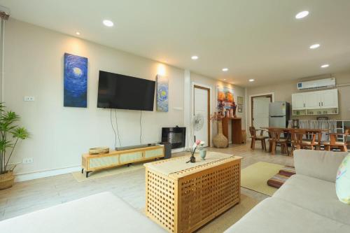 a living room with a couch and a tv on a wall at Silver Oak Valley บ่อเกลือสะปัน น่าน in Ban Kham