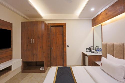 a bedroom with a bed and a wooden cabinet at Hotel Aerostay Residency Delhi Airport in New Delhi