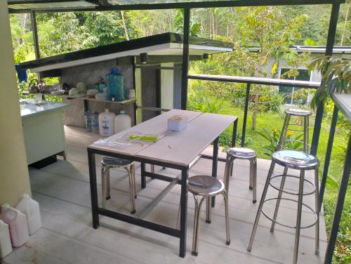 Una mesa y taburetes en un patio con cocina. en บ้านเล็กในป่าใหญ่โฮมสเตย์ กงหรา พัทลุง, en Ban Nai Mon