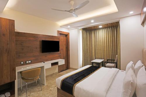 a bedroom with a bed and a desk and a tv at Hotel Aerostay Residency Delhi Airport in New Delhi