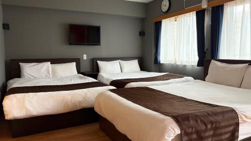 a hotel room with two beds with a clock on the wall at メゾン大通りパーク in Sapporo