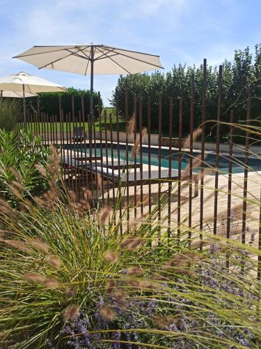 a fence with an umbrella next to a pool at Gîte de charme et spa prés d'Albi , Au Mas de Bel Air in Arthès