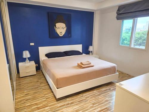 a bedroom with a large bed with a blue wall at Al Fiore Guesthouse Pattaya in Pattaya South