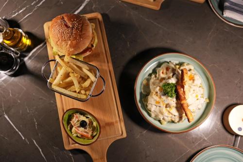 a table with a plate of food and a sandwich and fries at Movenpick Hotel Centaurus Islamabad in Islamabad