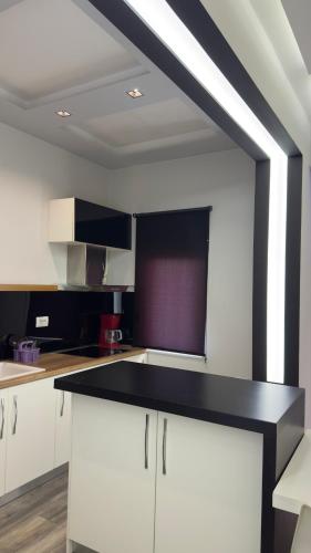 a kitchen with white cabinets and a black counter top at Luxury Suite Korca in Korçë