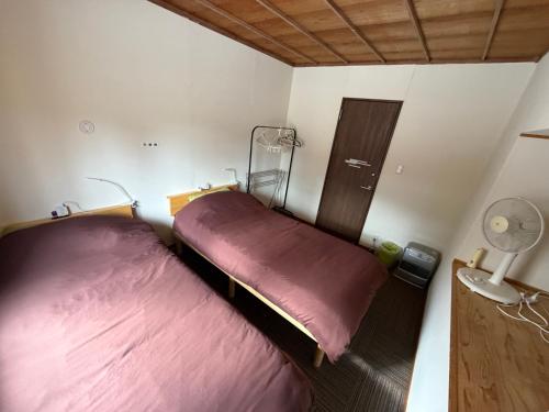 two beds in a small room with red sheets at Nori's Sharehouse Hakuba in Hakuba