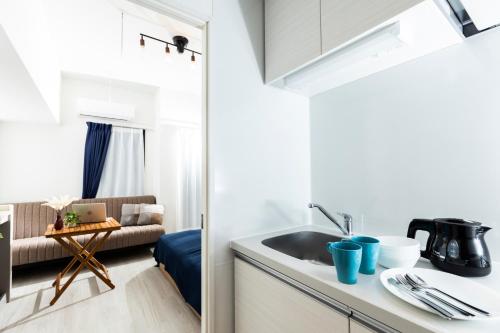 a kitchen with a sink and a couch in a room at Minn Umeda East in Osaka
