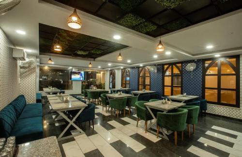 a dining room with tables and green chairs at Hotel The Prithvi Near Delhi Airport in New Delhi