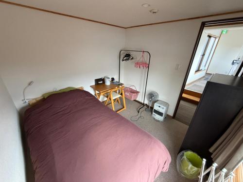 a bedroom with a pink bed and a window at Nori's Sharehouse Hakuba in Hakuba