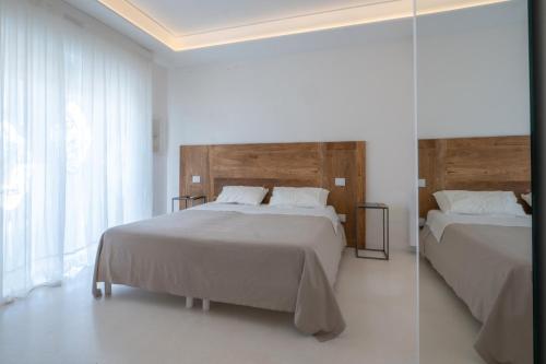 a bedroom with two beds and a glass wall at Valentino Luxury Rooms in Porto Cesareo