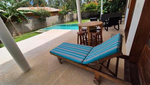 a bench on a porch with a table and a pool at la maison de la fontaine in Cap Skirring