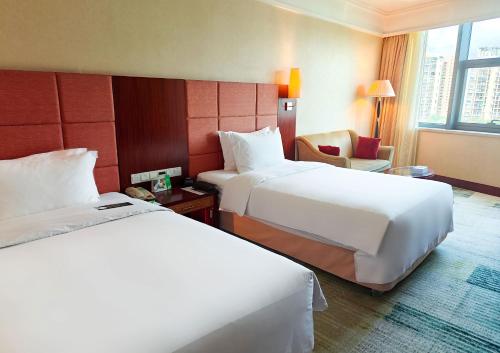 a hotel room with two beds and a chair at Holiday Inn Shenzhen Donghua by IHG in Shenzhen