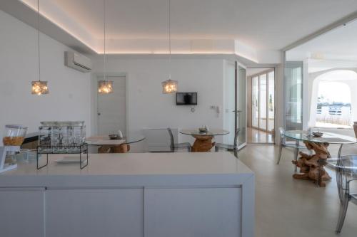 a white kitchen with tables and chairs in a room at Valentino Luxury Rooms in Porto Cesareo
