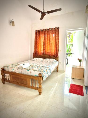 a bed in a room with an orange curtain at 3 BHK Row Villa in Benaulim