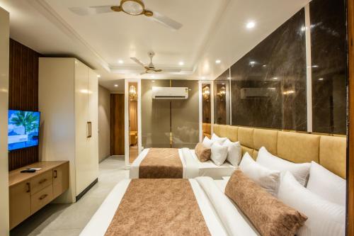 a bedroom with two beds and a flat screen tv at Hotel Aroma Plaza Delhi Airport in New Delhi