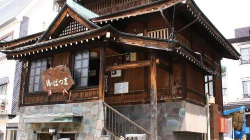 a large wooden building with a sign on it at Lodge Matsuya in Nozawa Onsen