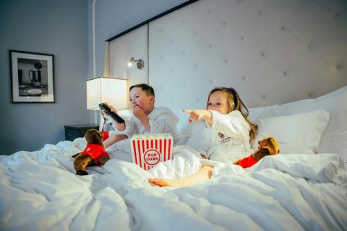 a man and a girl laying in a bed eating food at Palace Hotel, a Luxury Collection Hotel, San Francisco in San Francisco