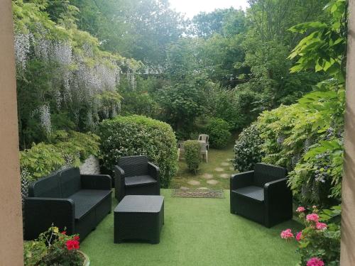a garden with two black chairs on the grass at logement en campagne in Landemer
