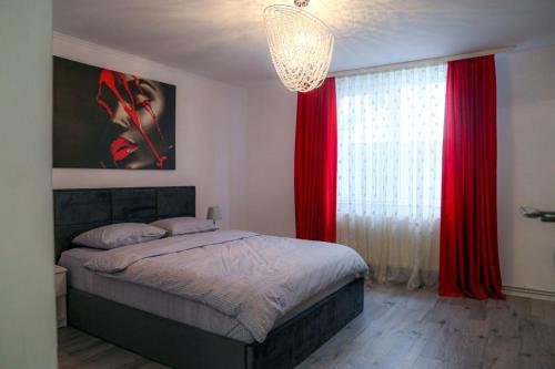 a bedroom with a bed with red curtains and a chandelier at Azur House2 in Cluj-Napoca