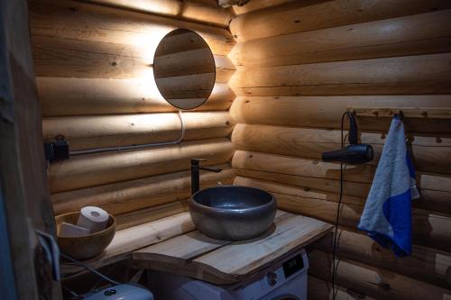 a wooden bathroom with a sink and a mirror at Design Cabin with Jacuzzi, Sauna & Nature in Pertunmaa