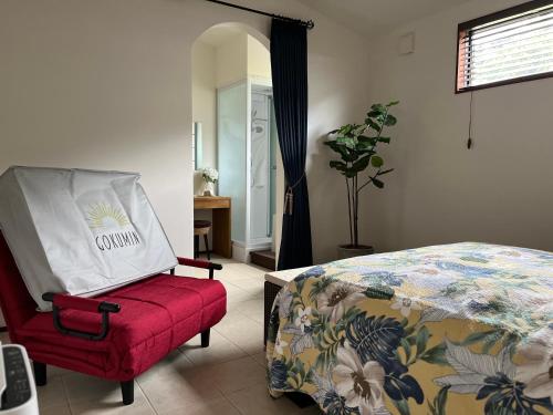 a bedroom with a bed and a red chair at Onomichi Villa Ayah in Onomichi