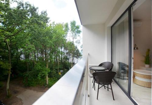a balcony with two chairs and a table on it at Dwie Sosny z sauną, Sun & Snow in Ustronie Morskie