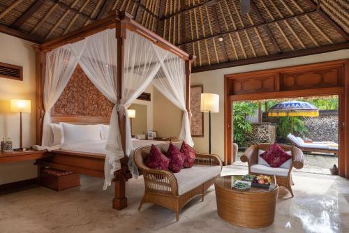 Un dormitorio con una cama con dosel y una silla. en The Oberoi Beach Resort, Bali, en Seminyak