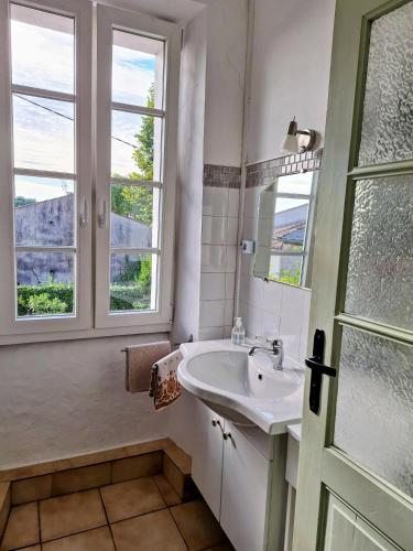 a white bathroom with a sink and two windows at Gemütliches altes Landhaus in Alaigne