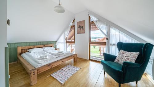 a bedroom with a bed and a blue chair at Ostoja Bukowo, Sun & Snow in Borowy Młyn