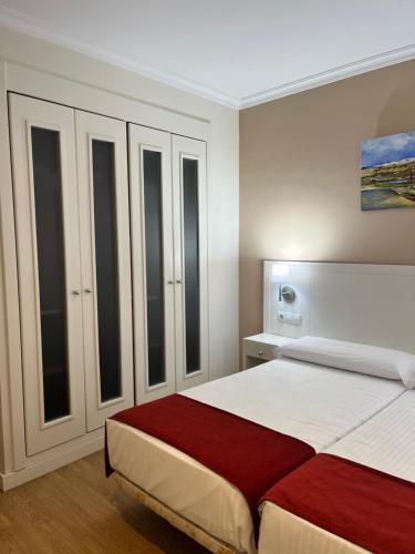 a bedroom with a large bed and some windows at Hostal Al-Andalus in Conil de la Frontera