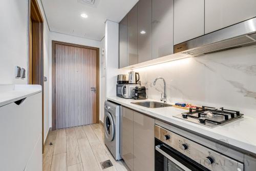 a white kitchen with a sink and a dishwasher at GLOBALSTAY Azizi Riviera 45 in Dubai