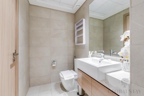 a bathroom with a white sink and a toilet at GLOBALSTAY Azizi Riviera 45 in Dubai