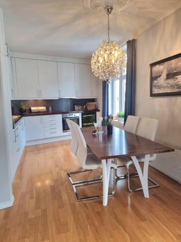 a dining room with a wooden table and white chairs at Central, lovely apartment with a unique view in Bergen