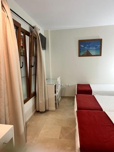a bedroom with a red bed and a window at Hostal Al-Andalus in Conil de la Frontera