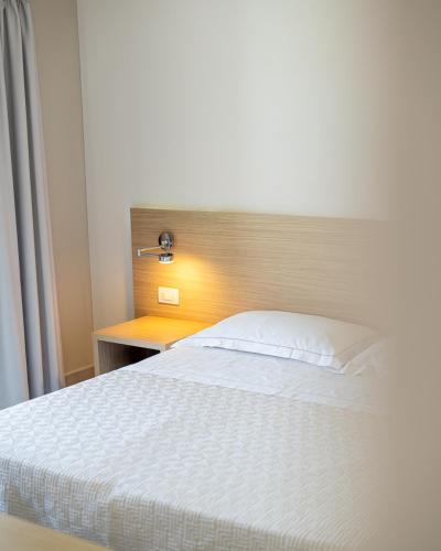a bedroom with a white bed and a wooden headboard at Hotel San Teodoro in San Teodoro