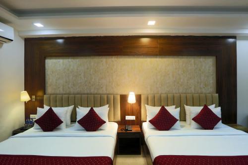 two beds in a hotel room with red pillows at Hotel The Prithvi Near Delhi Airport in New Delhi