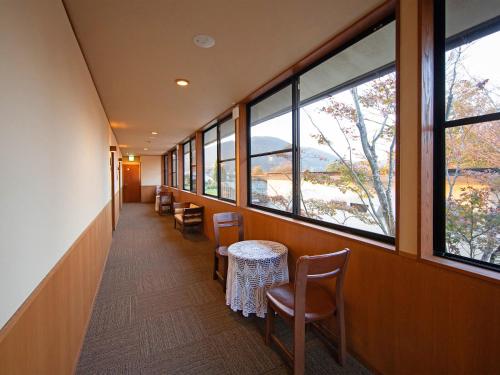 a hallway with chairs and tables and windows at Yufuin Onsen Ryokan Hananomai in Yufuin