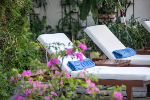 two white chairs in a garden with flowers at ÊMM Hotel Hue in Hue