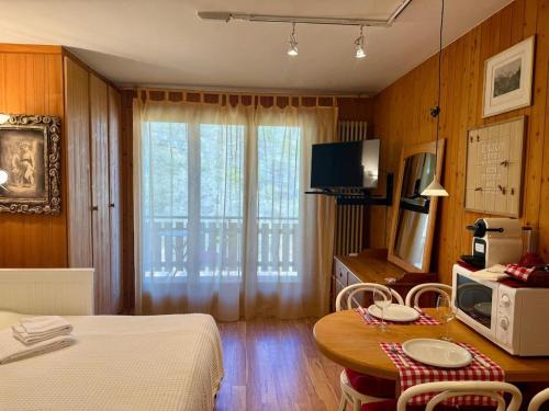 a room with a bed and a table with a microwave at Charmant studio au centre de la station in Nendaz