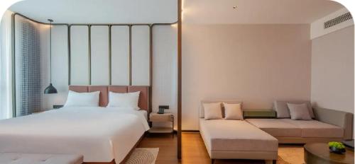 a bedroom with a large white bed and a couch at Tongpai Hotel, Zhong'an Chuanggu, Hefei High-tech Zone in Hefei