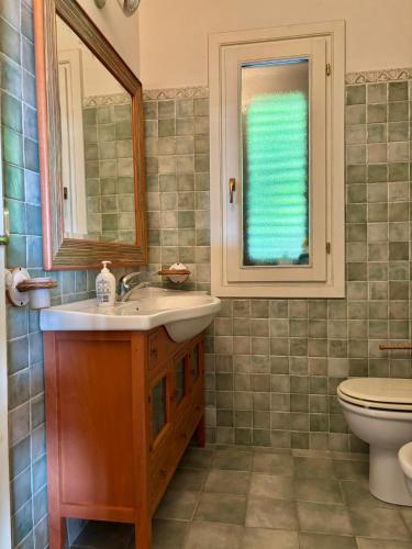 a bathroom with a sink and a toilet and a window at Villa Oleandro in Costa Paradiso